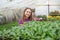 happy teen girl florist planting pot plants in greenhouse, gardener