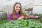happy teen girl florist planting pot plants in greenhouse, gardening