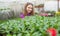 happy teen girl florist planting pot plants in greenhouse, selective focus, summer