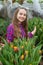 happy teen girl florist planting pot plants in greenhouse, spring