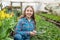 happy teen girl florist planting pot plants in greenhouse, spring