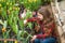 happy teen girl florist planting pot plants in greenhouse, summer