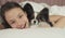 Happy teen girl kisses and plays with dog Papillon in bed