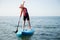 Happy teen girl paddling on sup board in Baltic sea