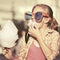 Happy teen girl in sunglasses eating cotton candy in city street