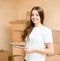 Happy teen girl with tablet computer standing on a background of boxes