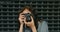 Happy Teen Girl Taking Photo By Vintage Film Camera In Front Of Metal Fence