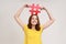 Happy teen girl with toothy smile in yellow t-shirt holding red hashtag sign board on head, tagging