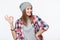 Happy teen girl wearing checkered shirt and beanie hat gesturing OK sign