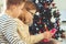 Happy teen siblings children or friends playing games with tablet on sofa near christmas tree at home