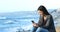 Happy teen texting on phone on the beach