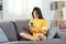 Happy teen in yellow using phone at home