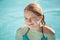 Happy teenage blond girl winks in outdoor pool
