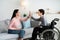 Happy teenage boy in wheelchair high fiving his mother at home, side view