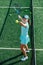 Happy teenage girl training on a new tennis court, throwing ball up and serving