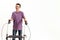 Happy teenaged disabled boy with cerebral palsy smiling at camera, taking steps using his walker isolated over white