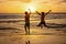 Happy teenager boys, running and playing on the beach on sunset, splashing water and jumping on the sand