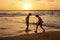 Happy teenager boys, running and playing on the beach on sunset, splashing water and jumping on the sand