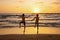 Happy teenager boys, running and playing on the beach on sunset, splashing water and jumping on the sand