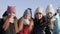 Happy teenager girl embracing and waving hands to camera on winter walk in frosty city. Portrait group young girl