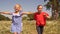 Happy teenager girls running on green field in summer countryside. Cheerful girls running on flowering meadow in village