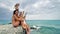 Happy teens sitting on beach pier having fun blowing kisses and waving hands