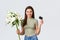 Happy tender young woman ordered bouquet of flowers delivery with credit card, smiling pleased and holding beautiful