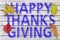 Happy Thanks Giving written on white wooden table with four autumn