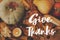 Happy Thanksgiving greeting card. Hand written Give Thanks text on background of pumpkins, autumn leaves, candle, warm lights on