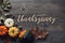 Happy Thanksgiving greeting text with pumpkins, squash and leaves over dark wood background