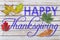 Happy Thanksgiving with several autumn leaf written on white wood