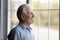 Happy thoughtful older 70s man looking out of window