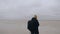 Happy thoughtful young man with backpack looking around, lost alone at endless cloudy low tide sandy desert slow motion.