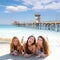 Happy three friends girls lying on beach sand smil