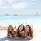 Happy three friends girls lying on beach sand smil