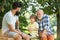 Happy three generations of men have fun and playing Chess in green park. Handsome grandpa and grandson are playing chess