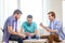 Happy three male friends playing poker at home