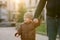 A happy three year old son walks hand in hand with his dad in the city