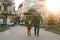 A happy three year old son walks hand in hand with his dad in the city on a sunny spring day