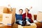 Happy tired couple sitting on couch in new home with cordboard boxes around