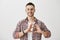 Happy to be in love with you. Studio shot of good-looking ordinary guy in glasses showing heart sign over chest, smiling