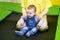 Happy toddler baby boy jumps on a trampoline with his mother in the p