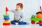 Happy toddler baby boy sorting colorful rings on pyramid