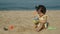 happy toddler baby girl playing sand toy on sea beach