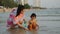 happy toddler baby girl playing toy and water with her mother on sea beach