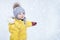 Happy toddler baby is playing in a yellow snowsuit. Child boy in warm c