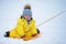 Happy toddler baby rides on an ice sled in the snow in a yellow snowsu