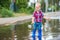 Happy toddler boy running through puddles in rubber boots. Child splashes after rain outside