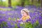 Happy toddler girl in bluebell flowers in spring forest