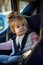 Happy toddler girl buckled into her car seat